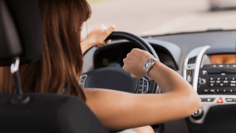 Temps de trajet domicile-travail trop long : quelle durée maximum ? Temps de trajet domicile-travail trop long : salariée regardant sa montre en se rendant au travail en voiture.
